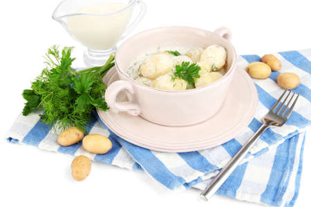 Tender young potatoes with sour cream and herbs in pan isolated on whiteの写真素材