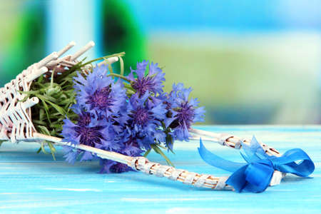 Beautiful bouquet of cornflowers in basket on blue backgroundの写真素材