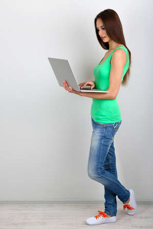 Beautiful young woman with laptop in roomの写真素材