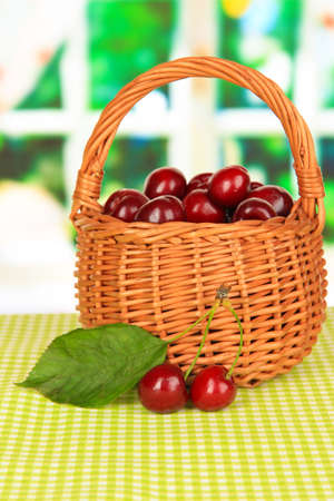Cherry berries in wicker basket on table in roomの写真素材