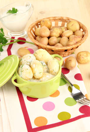 Tender young potatoes with sour cream and herbs in pan on wooden table close-upの写真素材
