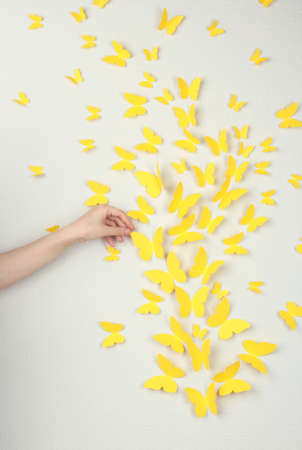 Paper yellow butterflies fly on wall in different directionsの写真素材