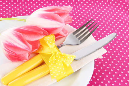 Festive dining table setting with tulips on pink polka-dot backgroundの写真素材