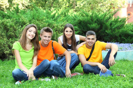 Happy group of young beautiful people sitting on  meadowの写真素材