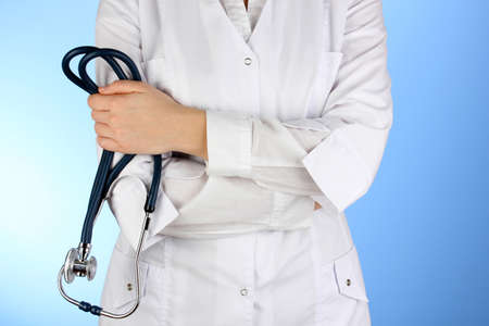Doctor with stethoscope in hands on blue backgroundの写真素材