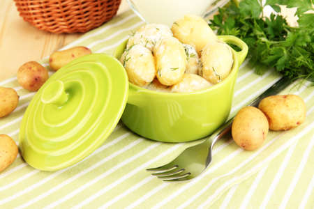 Tender young potatoes with sour cream and herbs in pan on wooden table close-upの写真素材