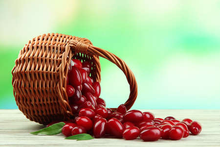 Fresh cornel berries in basket on wooden tableの写真素材