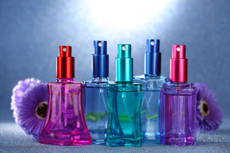 Women perfume in beautiful bottles and flowers on blue backgroundの写真素材
