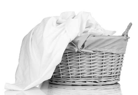 Rumpled bedding sheets in wicker basket isolated on whiteの写真素材