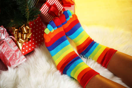 Legs in socks near Christmas tree on carpedの写真素材