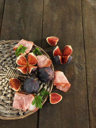 Tasty figs with ham on grey wooden tableの写真素材