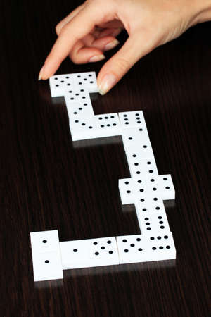 Hand playing dominoes on wooden backgroundの写真素材