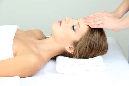 Beautiful young woman during facial massage in cosmetic salon close upの写真素材