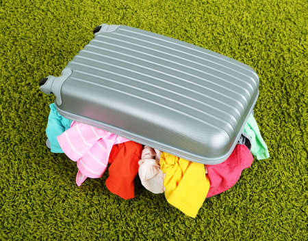 Suitcase with clothes on carpetの写真素材