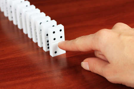 Hand pushing dominoes on wooden backgroundの写真素材