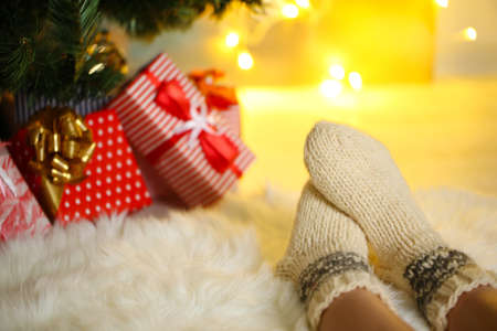 Legs in socks near Christmas tree on carpedの写真素材