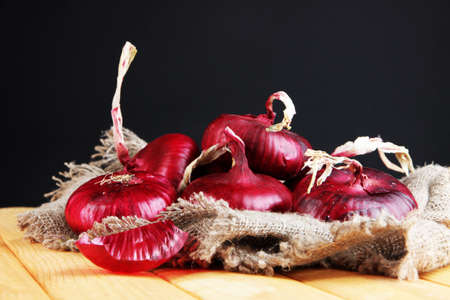 Fresh red onions on burlap on black backgroundの写真素材