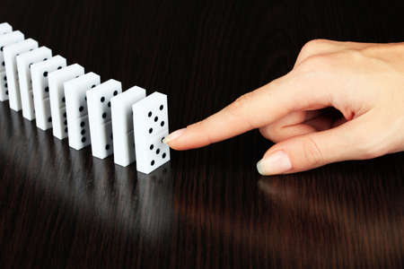 Hand pushing dominoes on wooden backgroundの写真素材