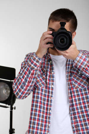 Handsome photographer with camera, on photo studio backgroundの写真素材