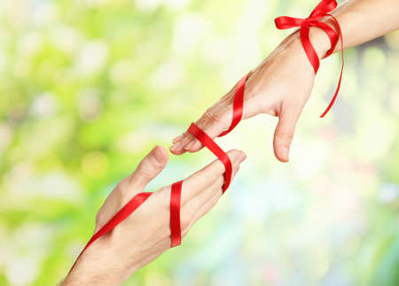Mans and girls hands tied with ribbon on bright backgroundの写真素材