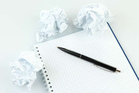 Crumpled paper balls with notebook and pen isolated on whiteの写真素材
