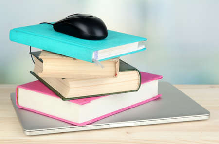 Computer mouse on books and notebook on wooden table on room backgroundの写真素材