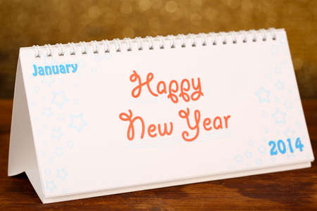 New Year calendar on wooden table, on shiny golden backgroundの写真素材