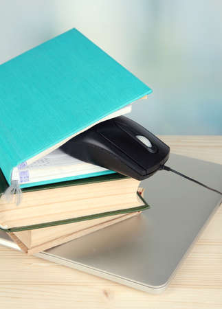 Computer mouse on books and notebook on wooden table on room の写真素材