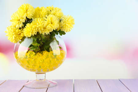 Beautiful flowers in vase with hydrogel on table on bright backgroundの写真素材