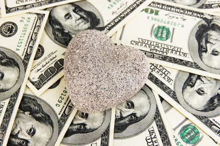 Love and money concept. Heart-shaped stone and American currency close up.の写真素材