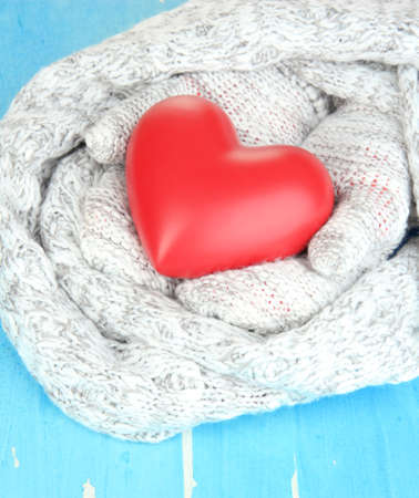 Female hands in mittens with heart on wooden backgroundの写真素材