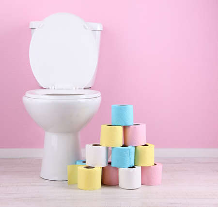 White toilet bowl and colorful rolls of toilet paper, in  bathroomの写真素材