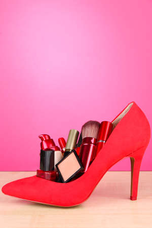 Beautiful red female shoe with cosmetics, on pink backgroundの写真素材