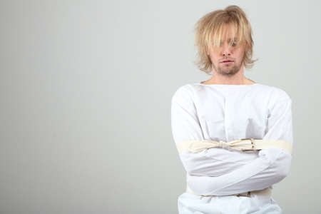 Mentally ill man in strait-jacket on gray backgroundの写真素材