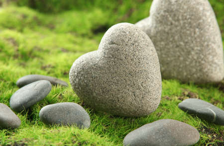 Grey stones in shape of heart, on grass backgroundの写真素材