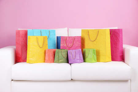 Colorful shopping bags on sofa, on color wall backgroundの写真素材