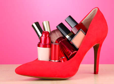 Beautiful red female shoe with cosmetics, on pink backgroundの写真素材
