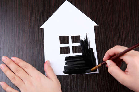 Female hand coloring paper cabin, on wooden backgroundの写真素材