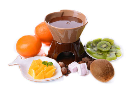 Chocolate fondue with sliced fruits, isolated on whiteの写真素材