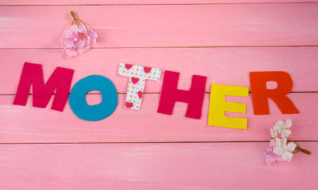 Mother- lettering of handmade paper letters on pink wooden backgroundの写真素材