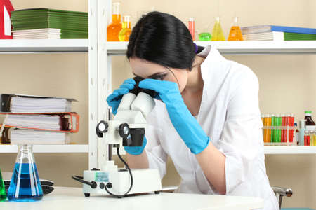 Young female scientist looking at microscope in chemistry laboratory の写真素材