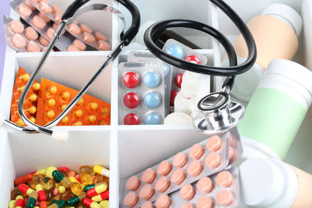 Medical pills, ampules in wooden box, on color backgroundの写真素材