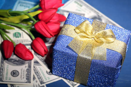 Gift box with money and flowers on color wooden backgroundの写真素材