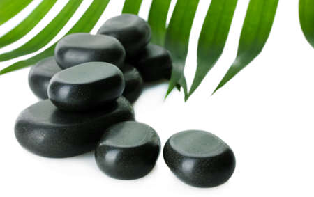 Spa stones and green palm leaf isolated on whiteの写真素材