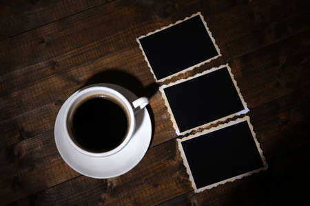 Coffee cup and old blank photos, on wooden backgroundの写真素材