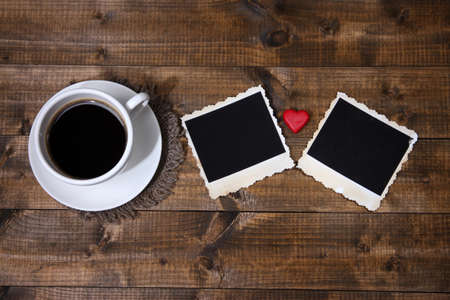 Composition with coffee cup, decorative hearts and old blank photos, on wooden backgroundの写真素材