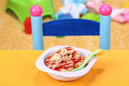 Bowl of porridge for baby and toys  on table, on toys backgroundの写真素材