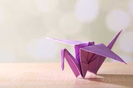 Origami crane on wooden table, on light backgroundの写真素材