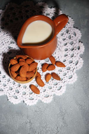 Almond milk in jug with almonds in bowl, on color wooden backgroundの写真素材