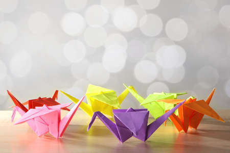 Origami cranes on wooden table, on light の写真素材